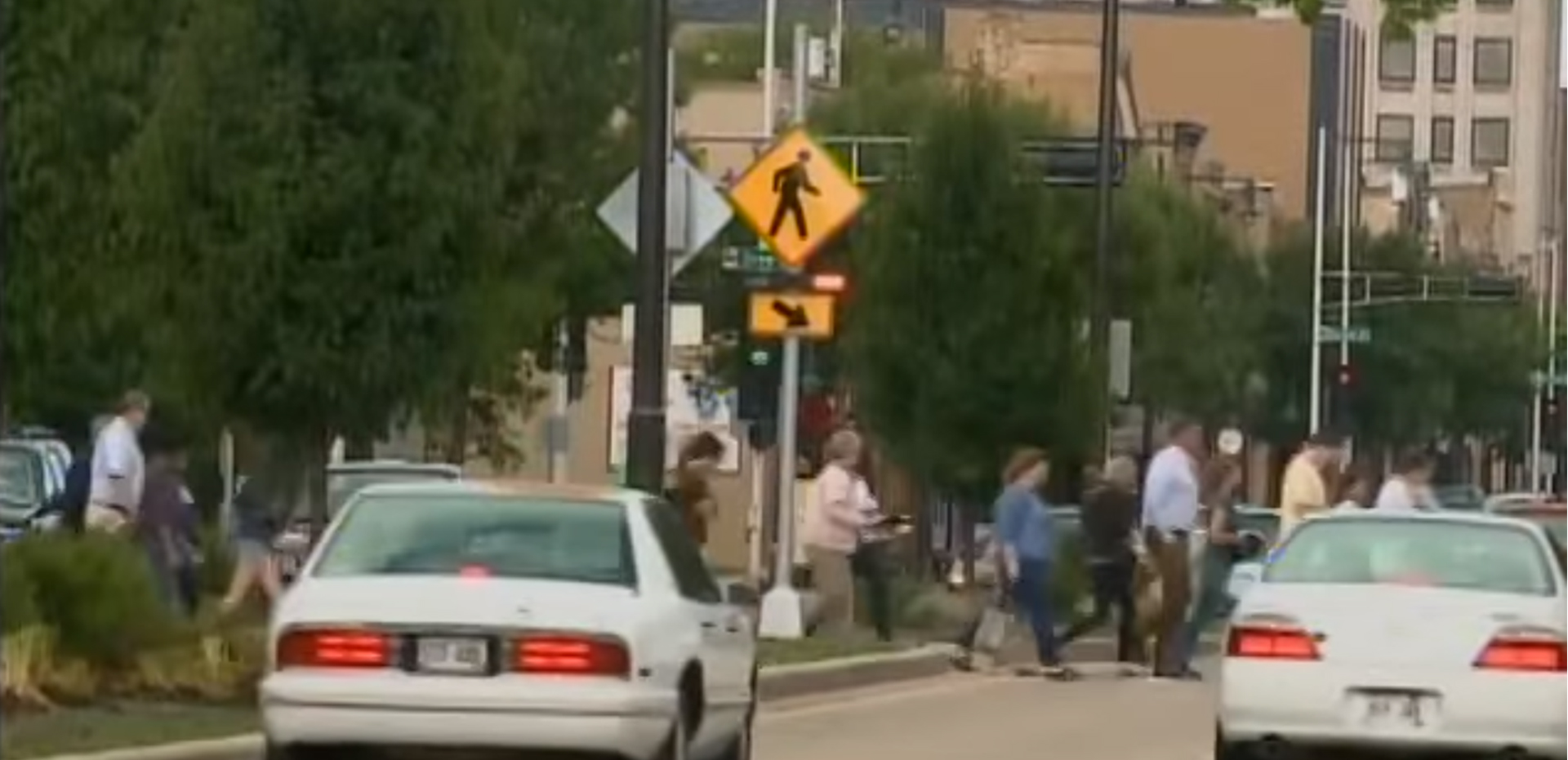 Students and other pedestrians crossing a busy street while cars are stopped.