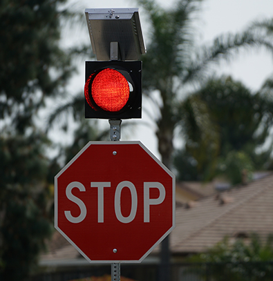 Traffic stop sign with red flashing beacon and solar mount on top of pole