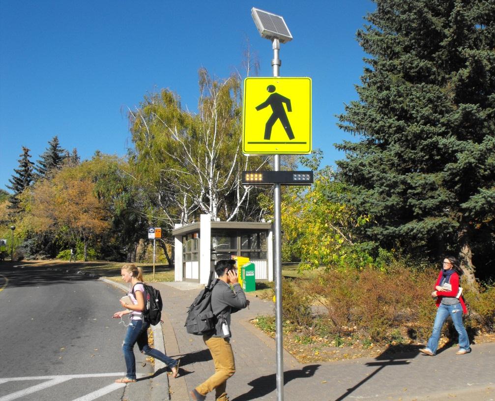 University students walking past an RRFB device at a crosswalk.