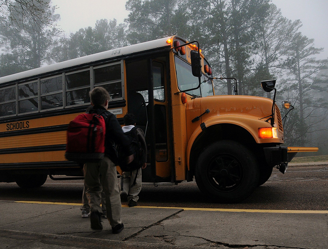 children getting on school bus