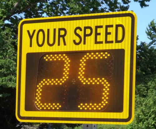 A digital "YOUR SPEED" radar speed sign with bright LEDs outdoors
